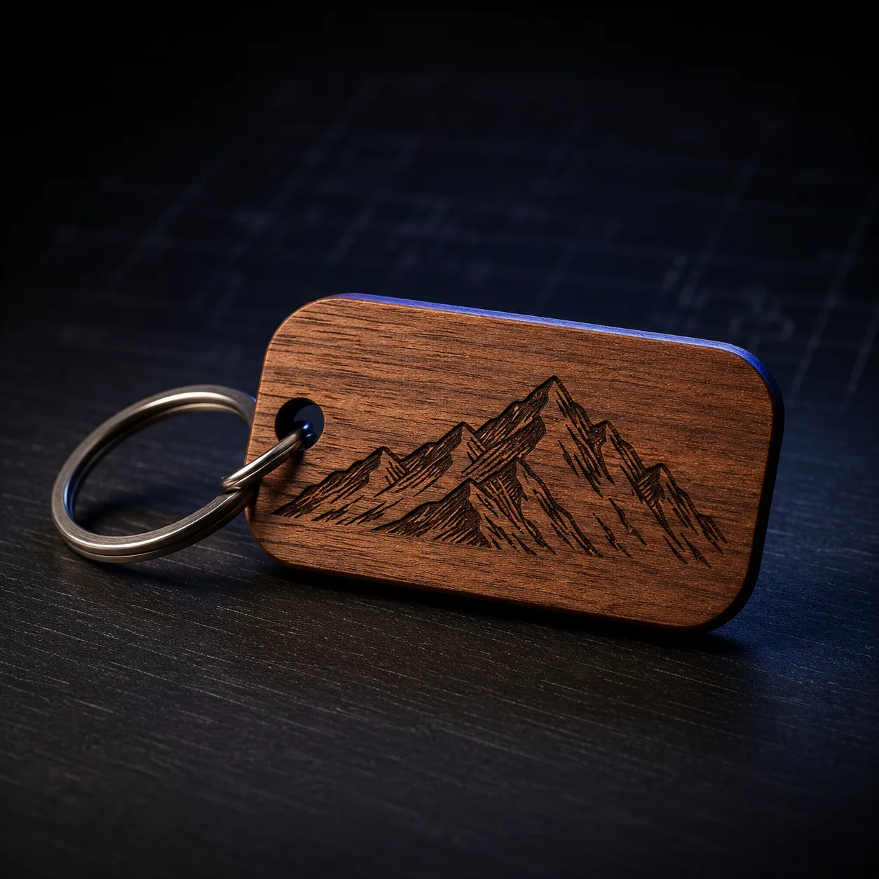 A walnut keychain laser-engraved with a mountain range